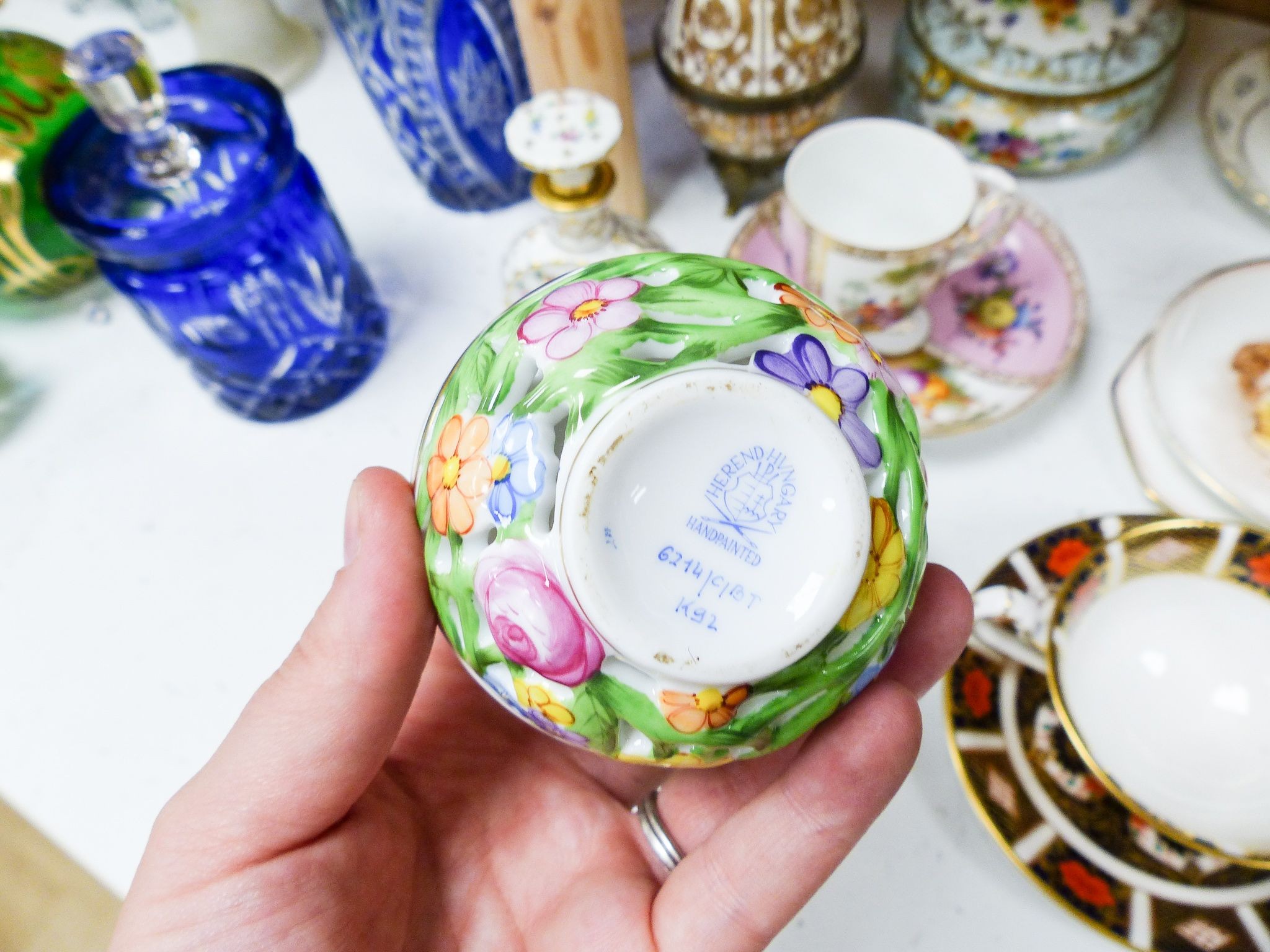 A group of Dresden and Continental porcelain cups and saucers boxes and covers and a scent bottle, 14 cm high